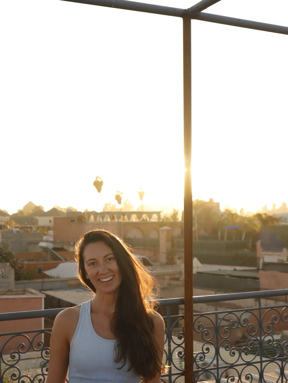 Issy Luck smiling on a rooftop terrace at sunset